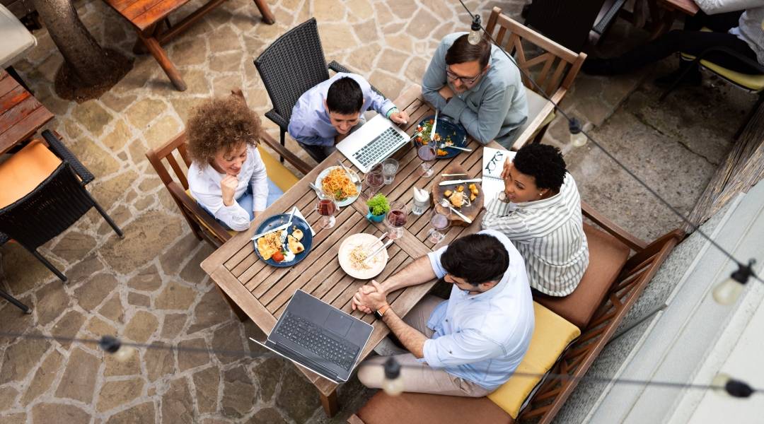 Group of people having food while looking at a laptop