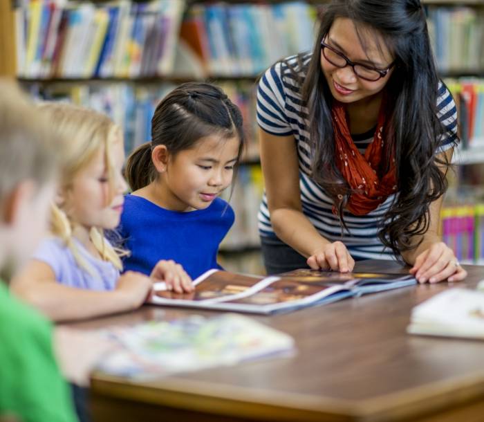 Lady teaching children in a library in a library